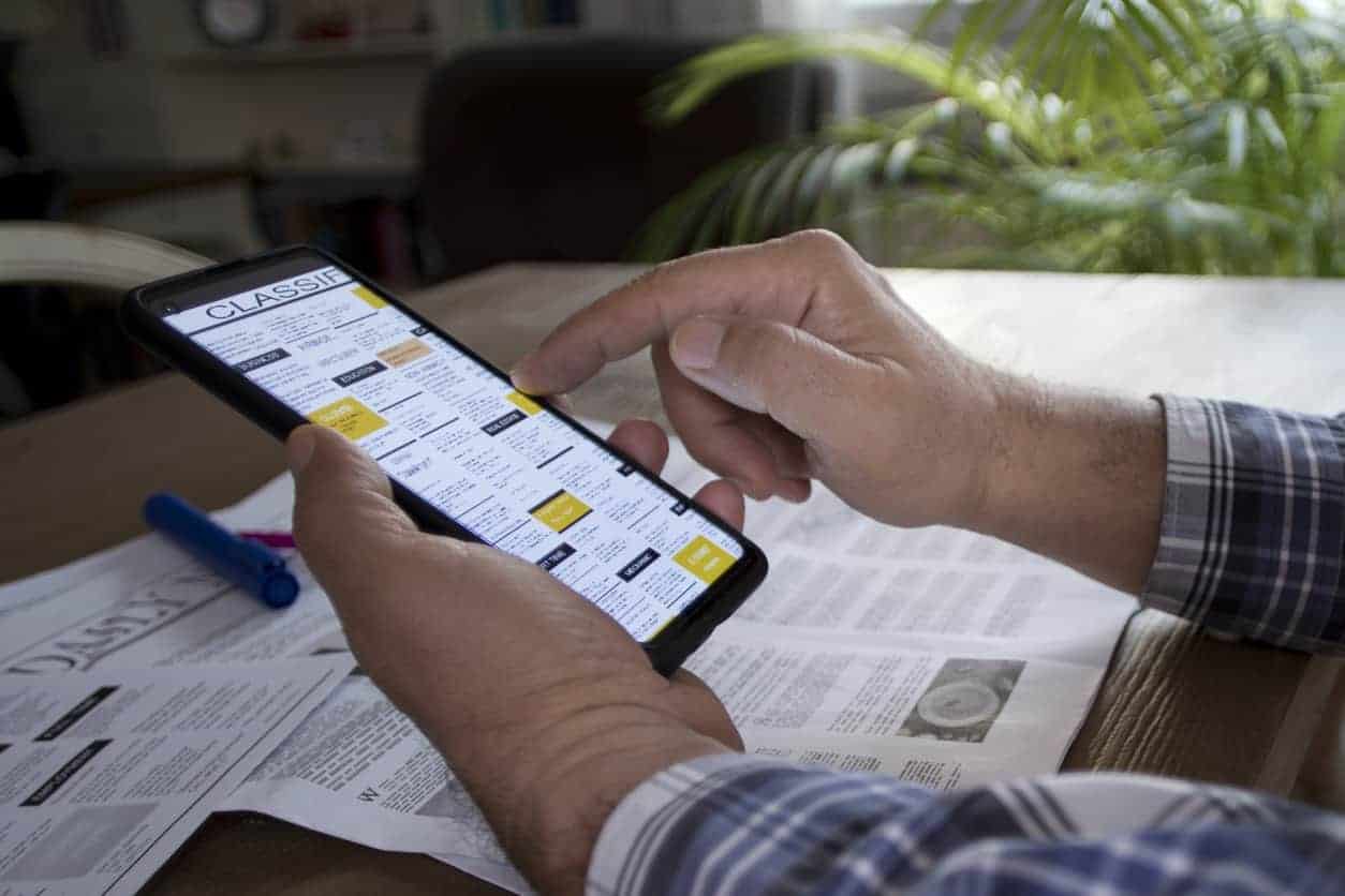 Man reading local business directory with laptop