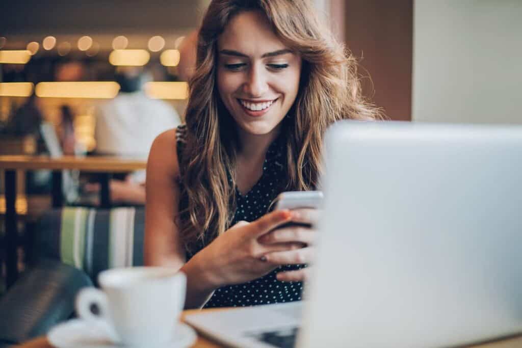 smiling female customer in a coffee shop; benefits of email marketing: customer communication