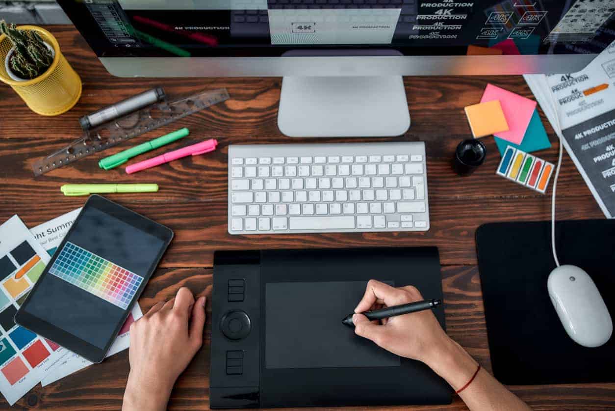 create stunning visuals Design tools. Top view of a designer using graphic tablet and working with computer while sitting at his workplace in the office. Top view of a workplace with graphic tablet, keyboard and computer.