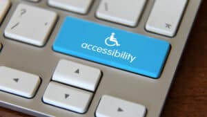 ADA Website Compliance - corner of laptop keyboard with blue accessibility key and wheelchair icon